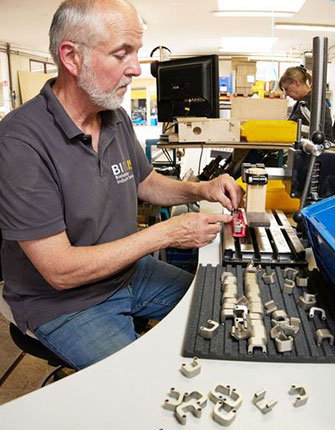 Ein Mitarbeiter montiert und sortiert Kleinteile